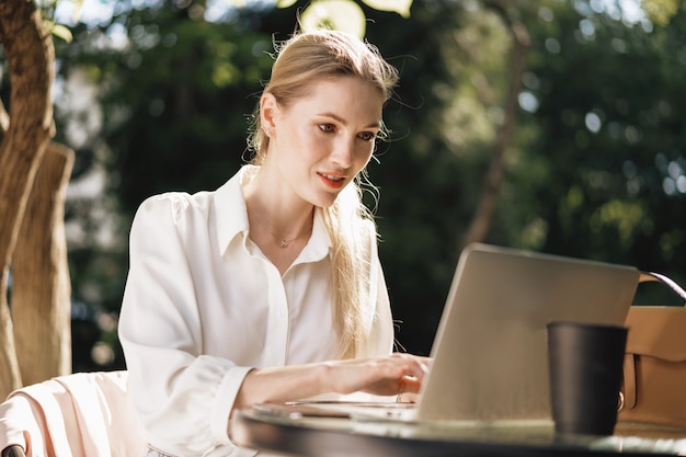 Jovem empresária de sucesso usando laptop para trabalhar ao ar livre