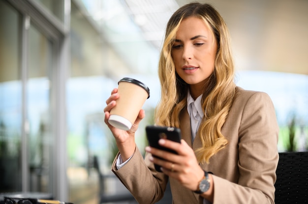 Jovem empresária em uma pausa para o café usando seu smartphone