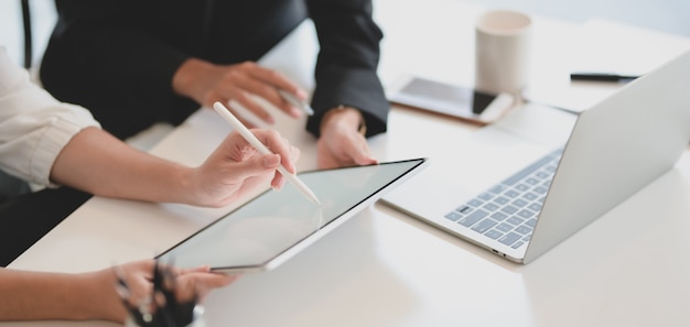 Jovem empresária explicando sua idéia ao seu colega de trabalho com tablet de tela em branco