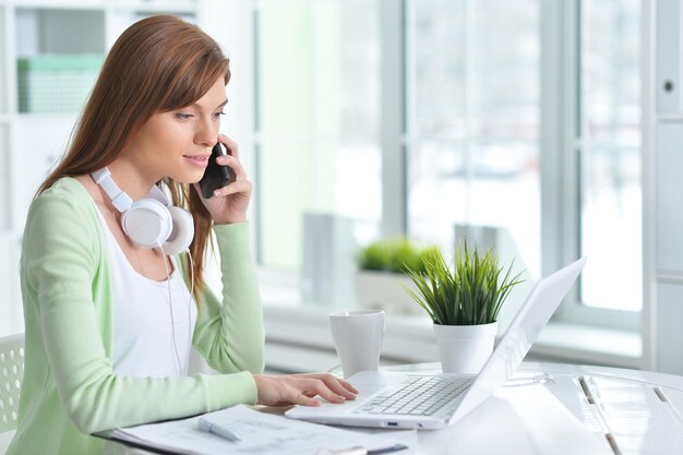 Jovem empresária falando no telefone enquanto está sentado no escritório