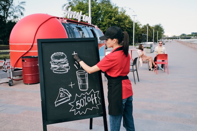 Jovem empresária fazendo desenhos de fast food no quadro-negro