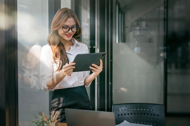 Jovem empresária feliz trabalhando com tablet no escritório corporativo