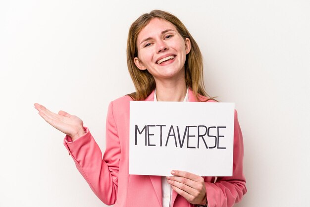 Jovem empresária inglesa segurando um cartaz do metaverso isolado no fundo branco, mostrando um espaço de cópia na palma da mão e segurando a outra mão na cintura