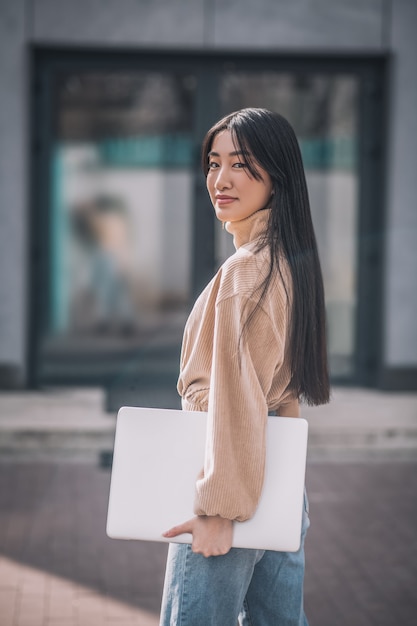 Jovem empresária. Jovem mulher asiática segurando um laptop e parecendo confiante