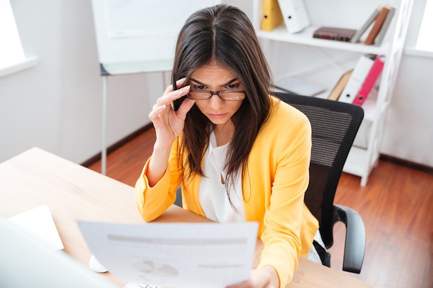 Jovem empresária lendo jornais no escritório