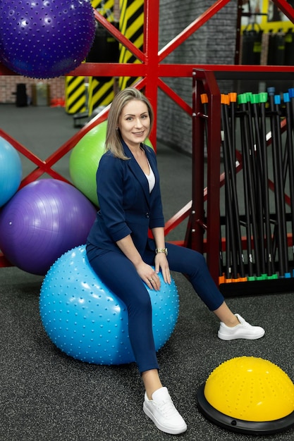 Jovem empresária linda de terno está envolvida em fitball, se divertindo e rindo.