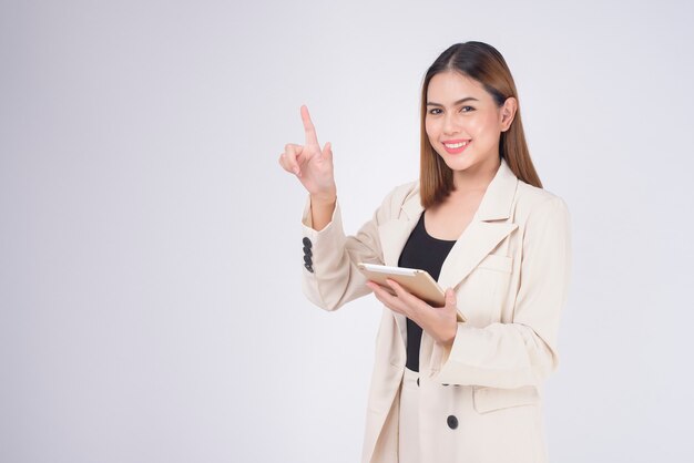 Jovem empresária linda em um terno segurando um tablet sobre fundo branco do Studio