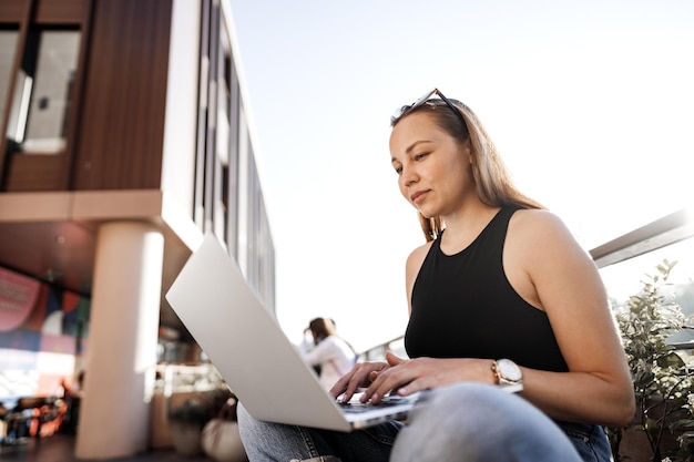 Jovem empresária loira usando laptop trabalhando no terraço em Istambul