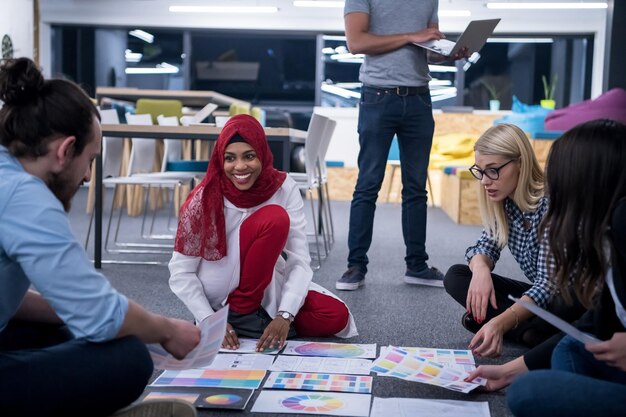 jovem empresária muçulmana negra tendo reunião com sua equipe de negócios de inicialização multiétnica no interior do escritório moderno, apresentando novas ideias no chão