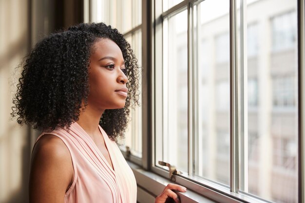 Jovem empresária negra a olhar pela janela.