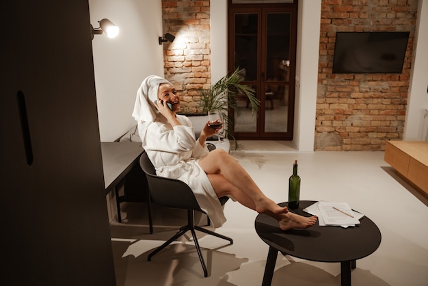 Jovem empresária ruiva tomando uma taça de vinho em casa após um longo dia de trabalho