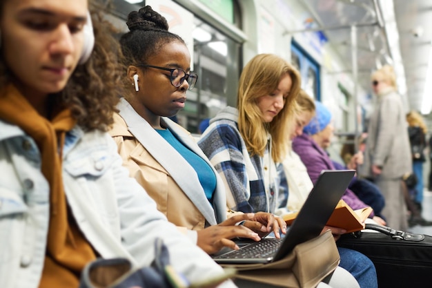 Jovem empresária séria em fones de ouvido digitando no teclado do laptop