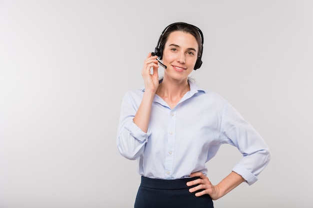 Jovem empresária sorridente em um fone de ouvido, consultando clientes enquanto fica isolado na sua frente