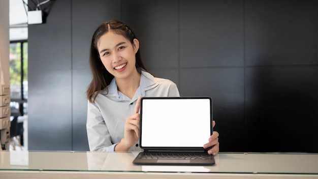 Jovem empresária sorridente segurando e mostrando o tablet do computador com tela vazia