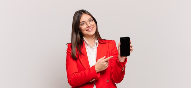 jovem empresária sorrindo alegremente, sentindo-se feliz e apontando para os lados e para cima, mostrando o objeto no espaço da cópia