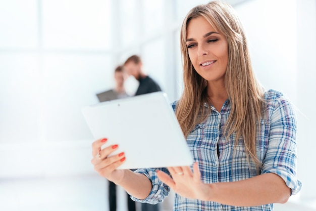 Jovem empresária usa um tablet digital em pé no escritório