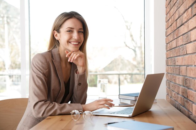 Jovem empresária usando laptop à mesa no escritório