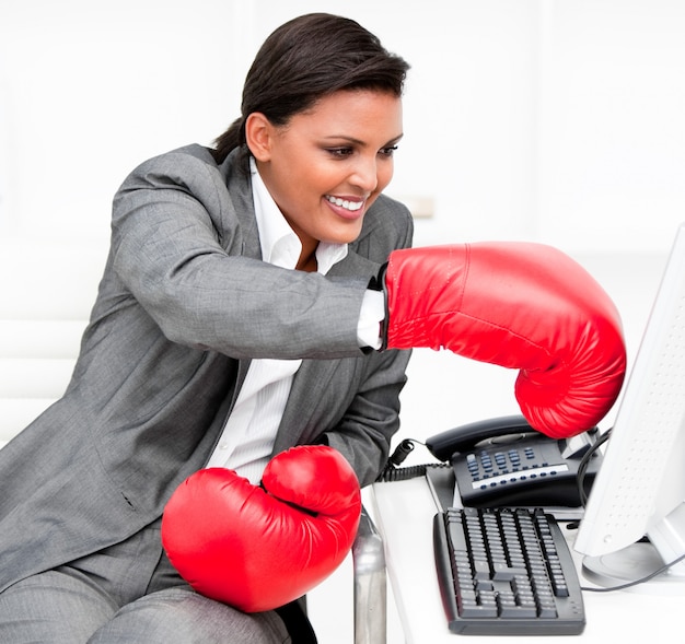 Jovem empresária usando luvas de boxe, socando um computador