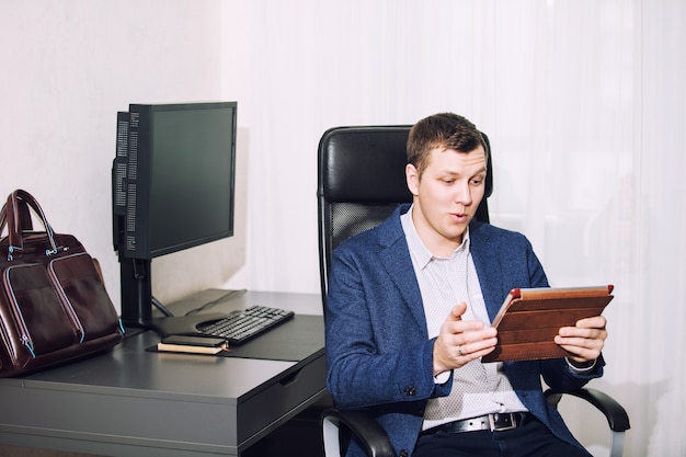 Jovem empresário adulto do sexo masculino em sua mesa com um computador no escritório durante o horário de trabalho
