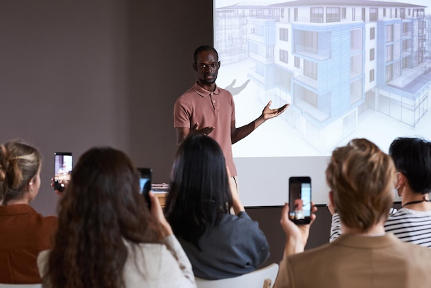 Jovem empresário africano apresentando novo projeto de novo prédio para pessoas na conferência