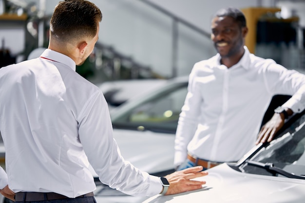 Foto jovem empresário africano faz perguntas sobre o carro apresentado na concessionária