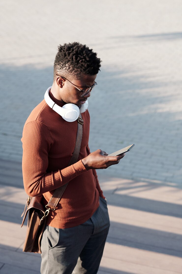 Foto jovem empresário africano rolando em smartphone em dia de verão
