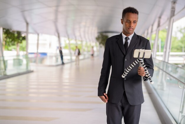 Jovem empresário africano usando telefone celular e fazendo vlogs ao ar livre na cidade