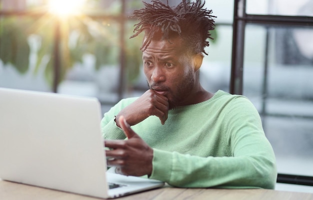 Jovem empresário afro-americano sentado em um escritório ou café trabalhando em uma nova inicialização de TI on-line