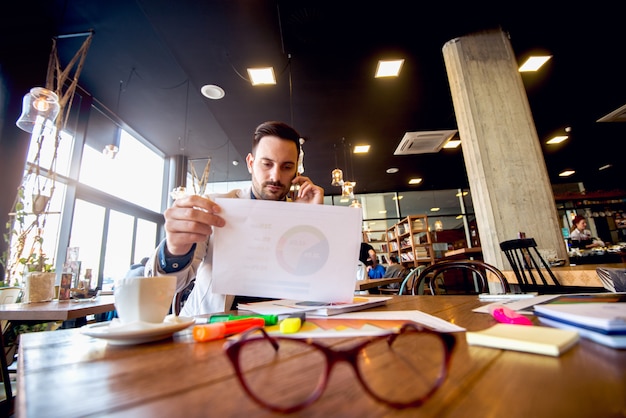 Jovem empresário, analisando resultados de negócios por telefone celular.