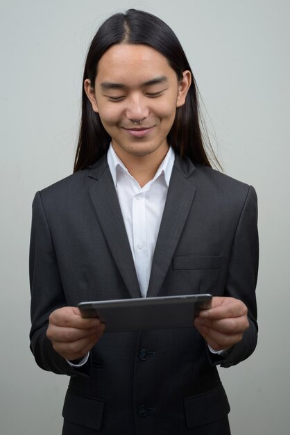 Jovem empresário asiático com cabelo comprido usando tablet digital