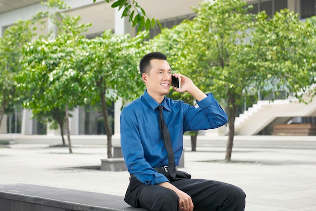 Jovem empresário asiático falando ao telefone