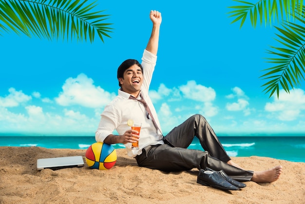Jovem empresário asiático indiano relaxando ou trabalhando na praia, aproveitando as férias