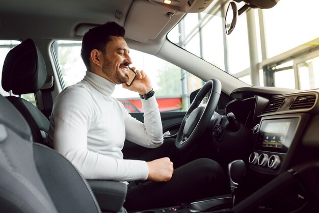 Jovem empresário atraente usando telefone celular inteligente no carro