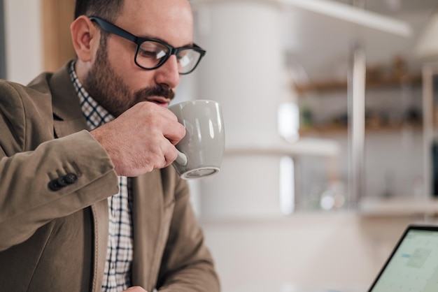 Jovem empresário bebendo café enquanto trabalhava na mesa do escritório