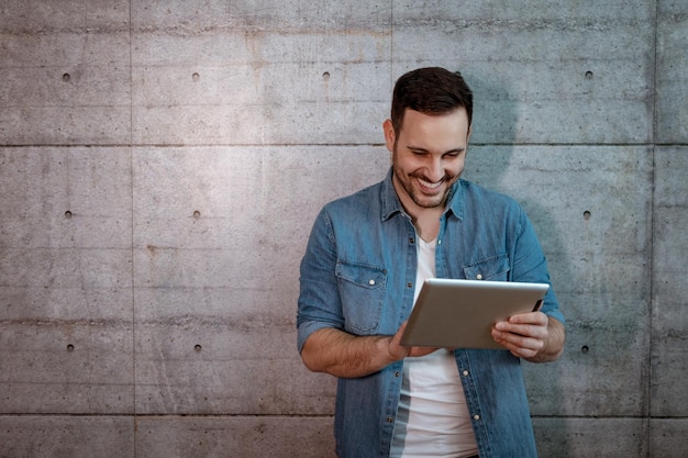 Jovem empresário bem sucedido bonito olhando em seu tablet, verificando os planos antes de começar a trabalhar no canteiro de obras.