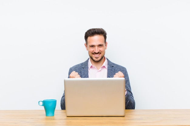 Jovem empresário bonitão gritando triunfante, rindo e se sentindo feliz e animado enquanto comemorava o sucesso