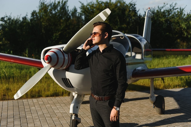 Jovem empresário bonitão perto de um avião particular