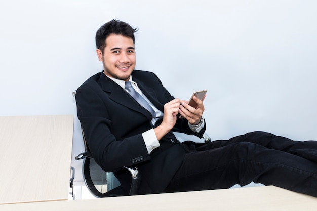 Jovem empresário bonitão sorrindo e falando com o telefone no escritório