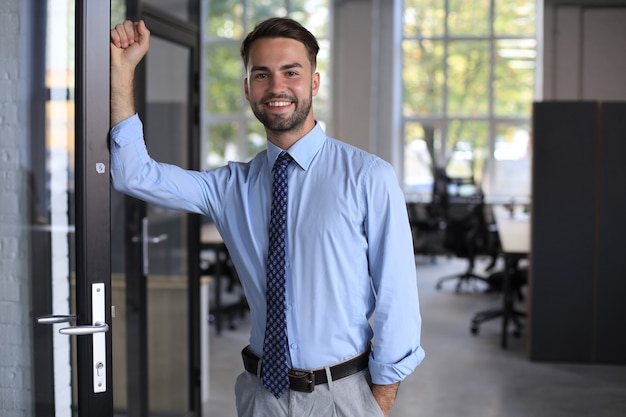 Jovem empresário bonitão sorrindo em um ambiente de escritório