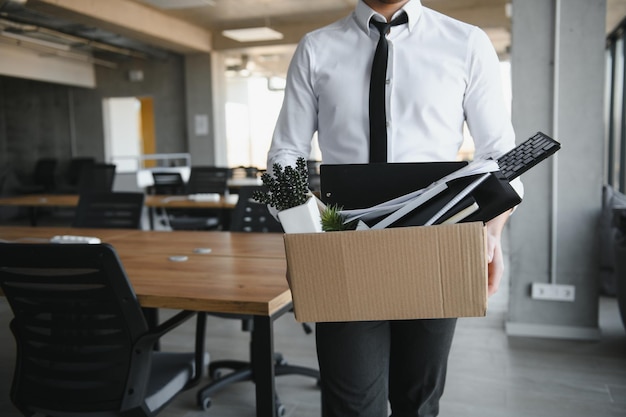 Jovem empresário bonito em escritório moderno leve com caixa de papelão Último dia de trabalho Trabalhador de escritório chateado é demitido