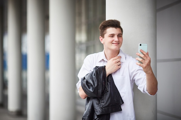 Jovem empresário bonito falando em vídeo, chamando em seu smartphone na rua