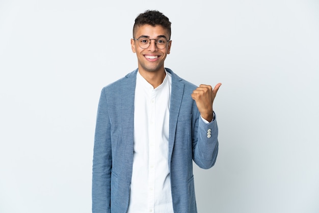 Jovem empresário brasileiro isolado em parede branca apontando para a lateral para apresentar um produto