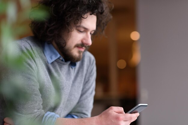 Jovem empresário casual segurando smartphone no escritório de inicialização