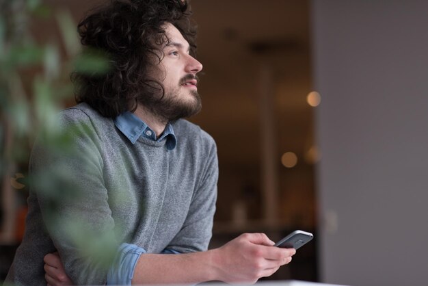 Jovem empresário casual segurando smartphone no escritório de inicialização