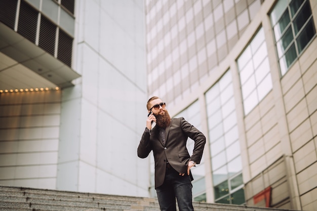 Jovem empresário com a barba falando ao telefone.