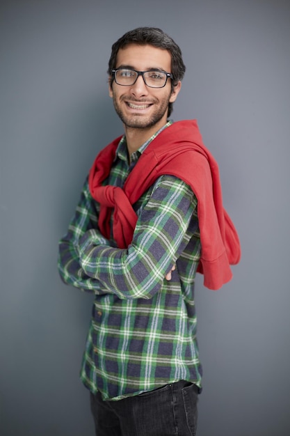 Jovem empresário com a barba por fazer posando contra o retrato de estúdio de fundo de parede cinza alcançando a carreira