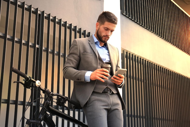 Jovem empresário com bicicleta e smartphone na rua da cidade