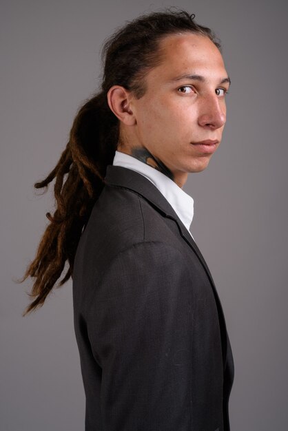 Jovem empresário com dreadlocks contra um fundo cinza