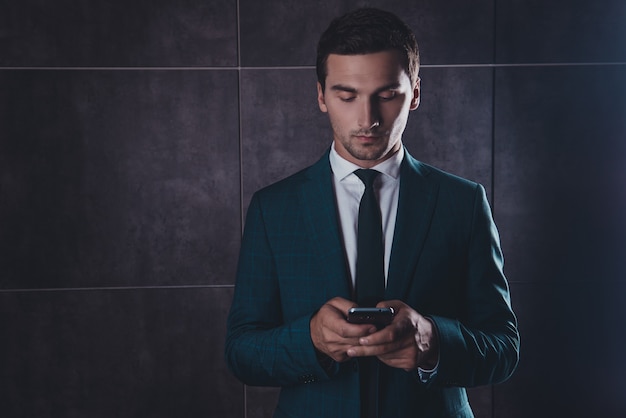 Jovem empresário concentrado conversando em smartphone em um espaço cinza