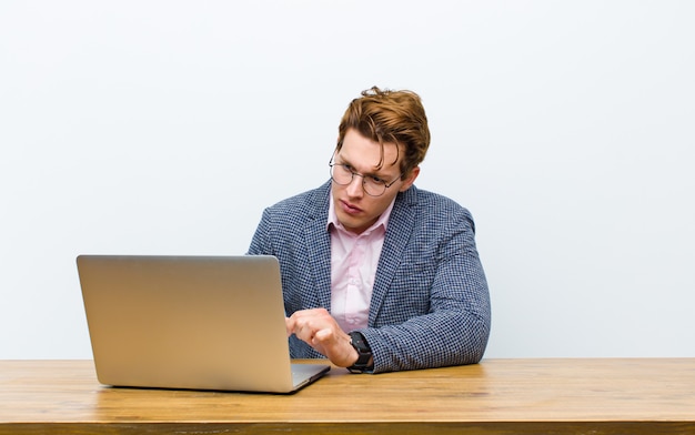 Jovem empresário de cabeça vermelha, trabalhando em sua mesa com um laptop